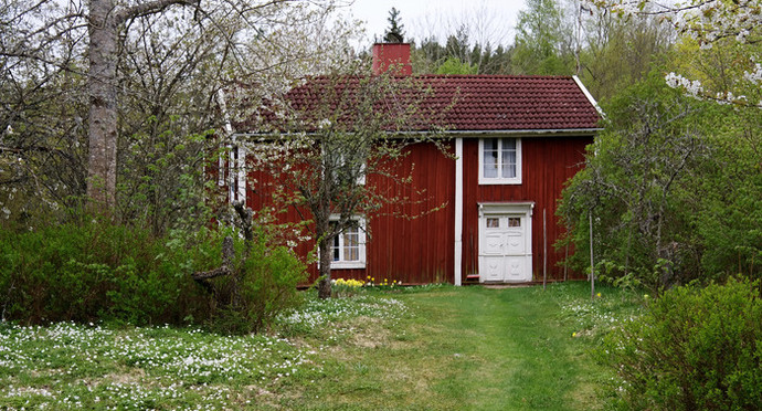 Röd stuga i lummiga Idekulla by